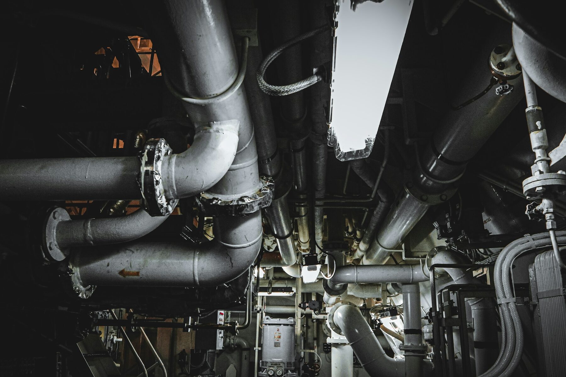 Dense network of metal pipes and equipment inside a vessel engine room